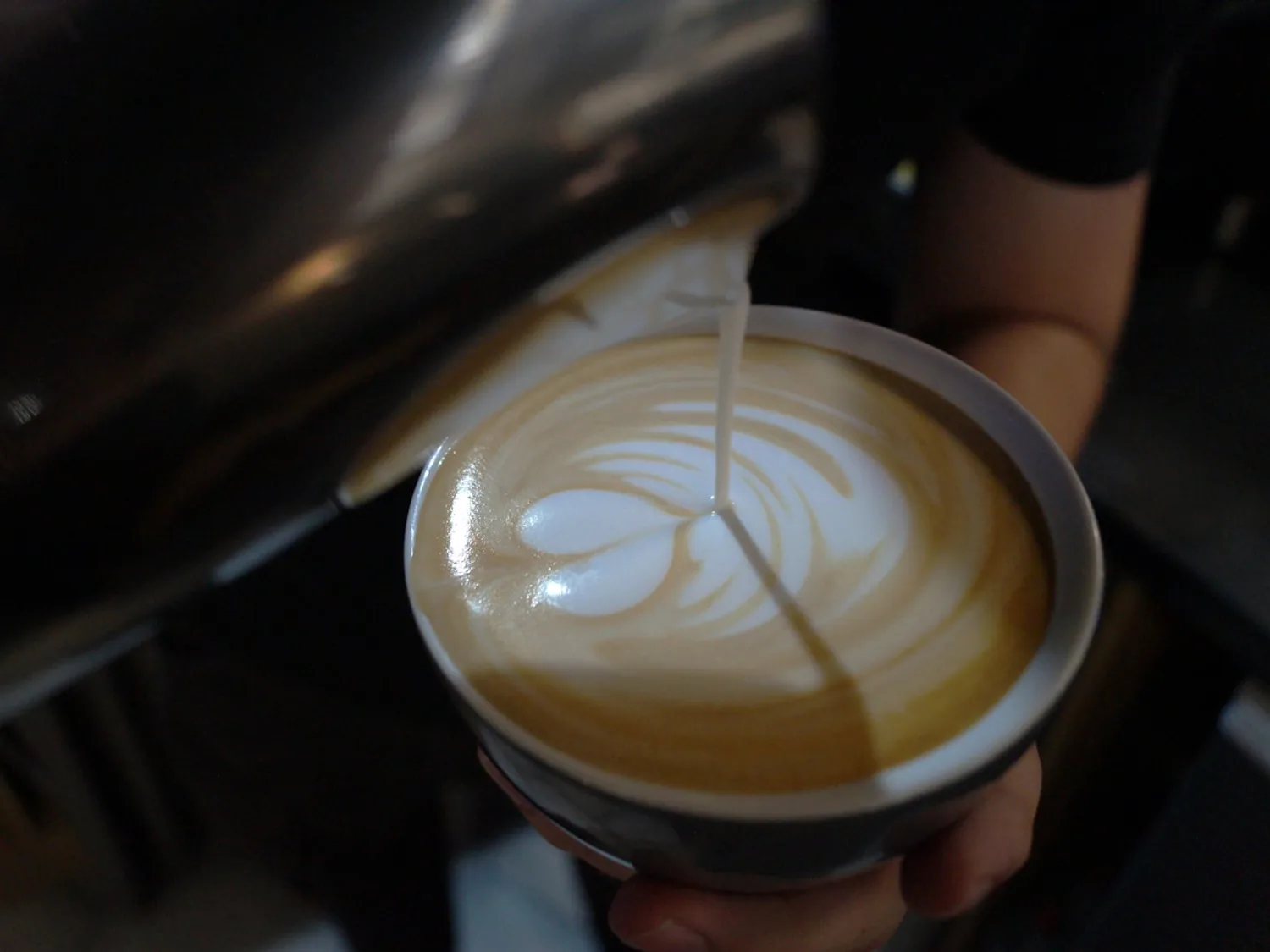 Barista pouring latte art into a cappuccino